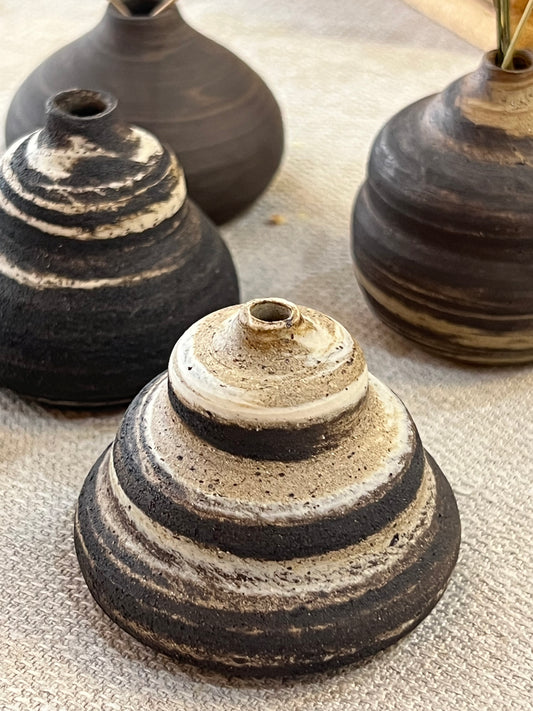 Set of black and beige ceramic vases on a textured surface