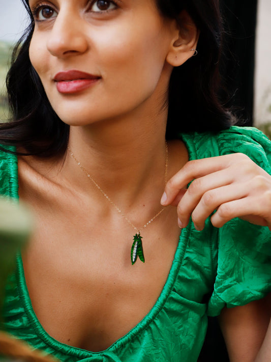 Lady in a green dress, weraing a playful peas in a pod pendant.